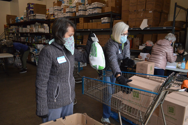 Volunteers Deena Snell and Nancy Bloedorm help load food into the cart during the pantry food giveaway Saturday afternoon.