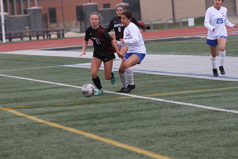 Huntley senior Maddie Cummings battles an Elgin Larkin player in a Huntley tournament match. Ashley Crisci (8) is ready to assist.