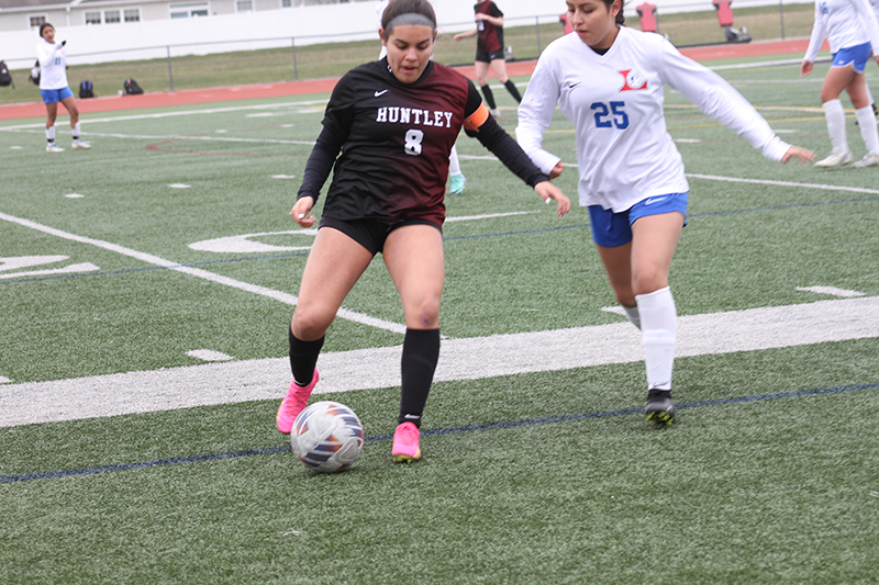 Huntley senior Ashlyn Cirsci battles an Elgin Larkin player for control of the ball. The Red Raiders won, 4-0, on March 30 to earn their own invitational championship.